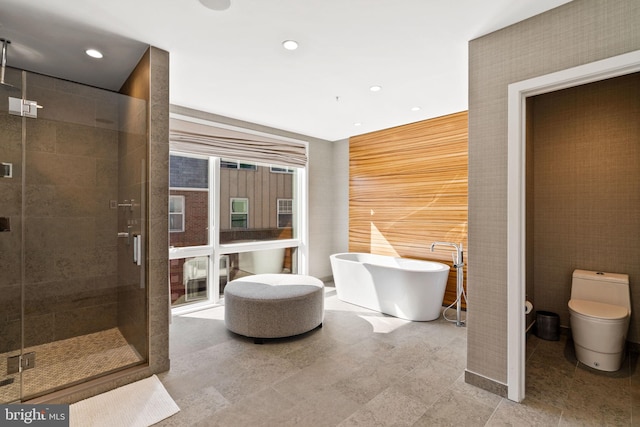 bathroom featuring shower with separate bathtub, toilet, tile flooring, and tile walls