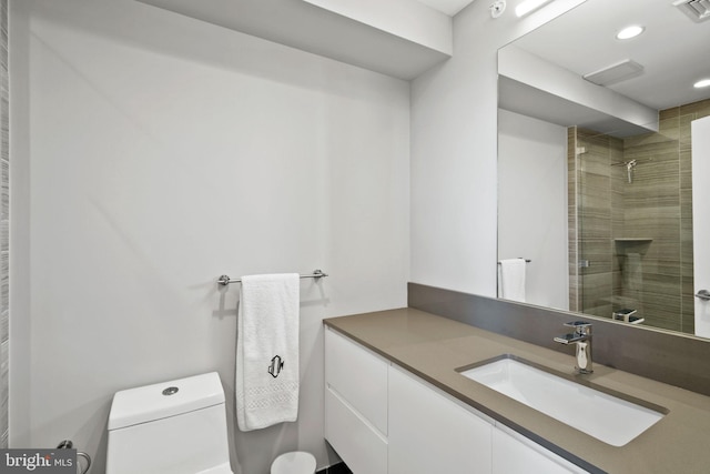 bathroom with toilet, vanity, and tiled shower