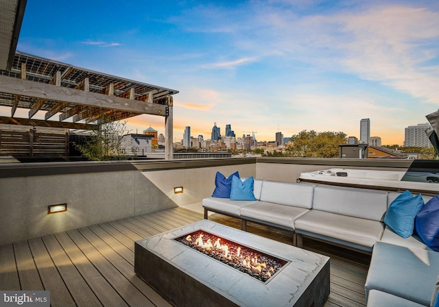 deck at dusk with an outdoor living space with a fire pit and a pergola