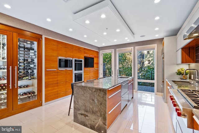 kitchen featuring light tile floors, a kitchen island with sink, stone countertops, sink, and a kitchen breakfast bar