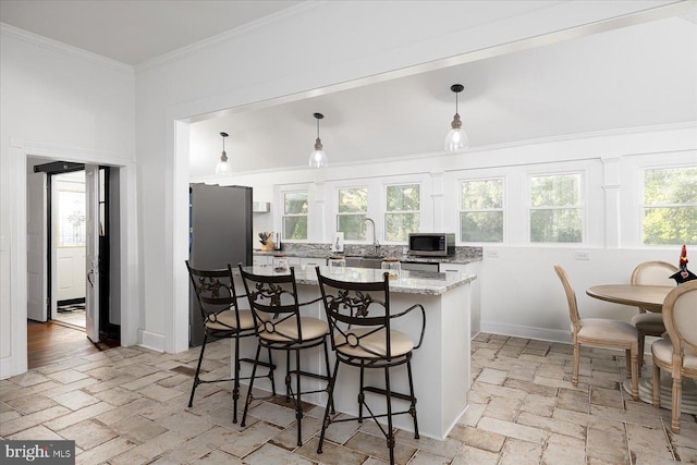 kitchen featuring pendant lighting, a center island, a kitchen breakfast bar, light stone countertops, and stainless steel appliances