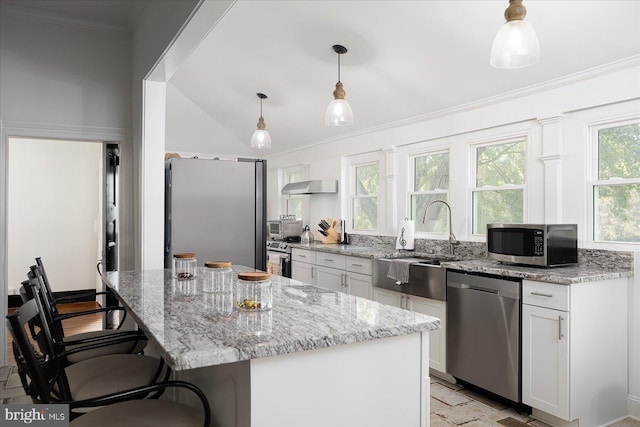 kitchen with decorative light fixtures, stainless steel appliances, white cabinetry, and a kitchen island