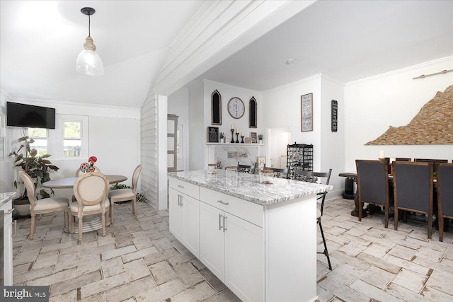 kitchen featuring light stone countertops, white cabinets, a center island, hanging light fixtures, and a breakfast bar area