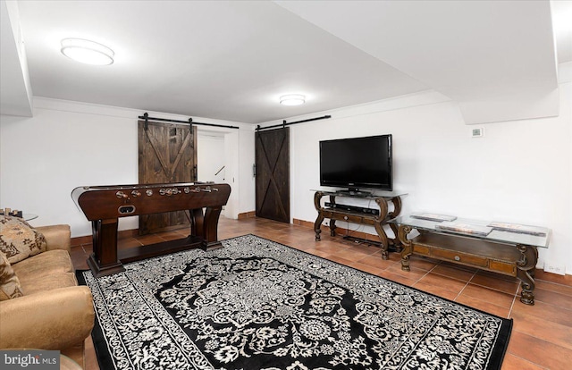 recreation room with a barn door, crown molding, and tile patterned flooring