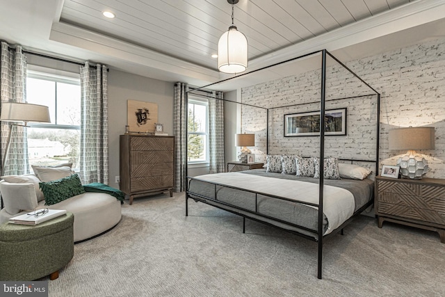 bedroom with a raised ceiling, brick wall, and carpet