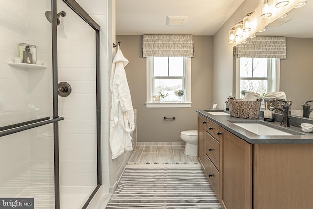 bathroom with toilet, double vanity, and a shower with shower door