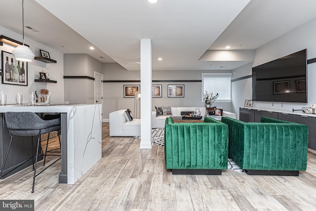 kitchen with light hardwood / wood-style floors, decorative light fixtures, and a kitchen breakfast bar