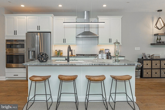 kitchen with hanging light fixtures, tasteful backsplash, stainless steel appliances, light hardwood / wood-style floors, and white cabinets