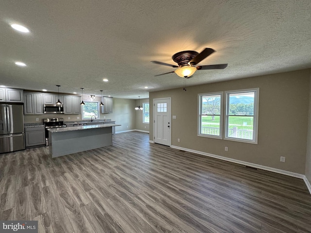 kitchen featuring appliances with stainless steel finishes, hanging light fixtures, dark wood-type flooring, ceiling fan, and gray cabinets