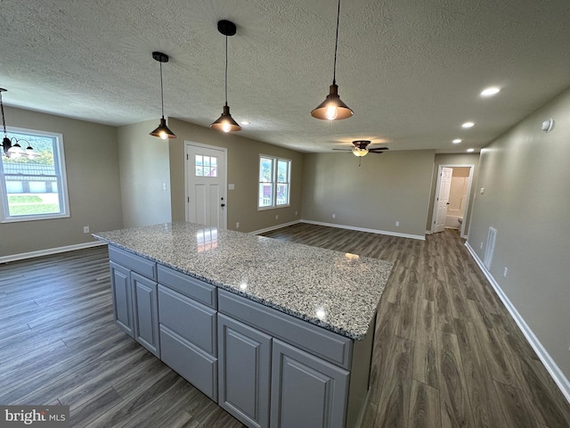 kitchen featuring dark hardwood / wood-style flooring, hanging light fixtures, and light stone counters