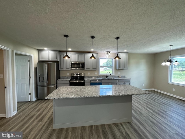 kitchen with plenty of natural light, stainless steel appliances, a notable chandelier, and dark hardwood / wood-style flooring