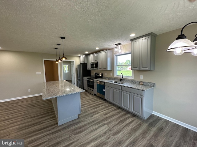kitchen with dark wood-type flooring, sink, stainless steel appliances, light stone counters, and gray cabinets