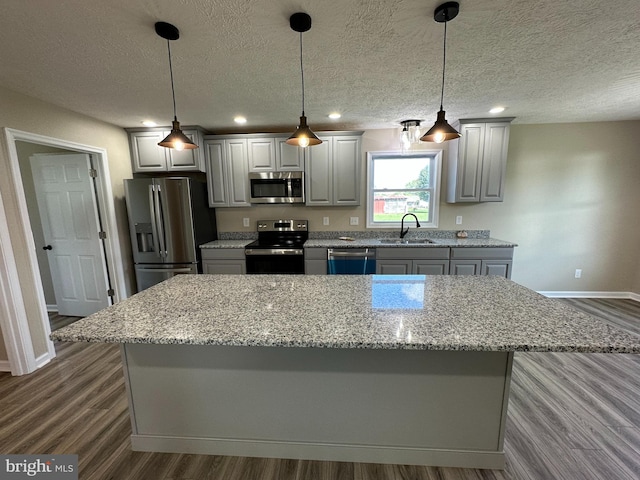 kitchen featuring gray cabinetry, hanging light fixtures, stainless steel appliances, and a center island
