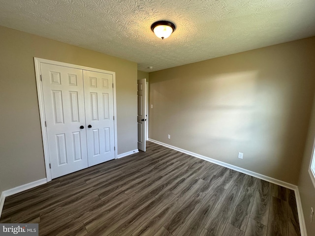 unfurnished bedroom with a closet, dark hardwood / wood-style floors, and a textured ceiling