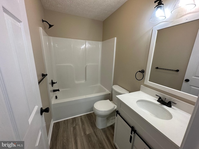 full bathroom featuring shower / bath combination, large vanity, a textured ceiling, toilet, and hardwood / wood-style flooring