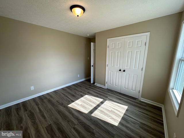 unfurnished bedroom with dark hardwood / wood-style flooring, a textured ceiling, and a closet
