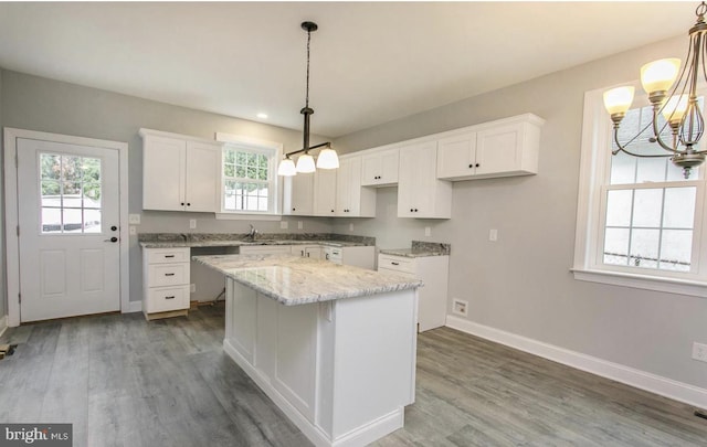 kitchen with white cabinetry, decorative light fixtures, a center island, and wood-type flooring