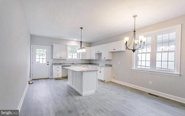 kitchen featuring white cabinets, light wood-type flooring, pendant lighting, and a center island