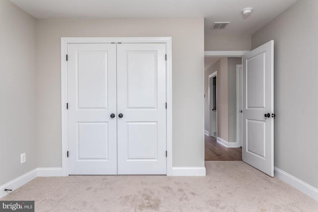 unfurnished bedroom with light carpet and a closet