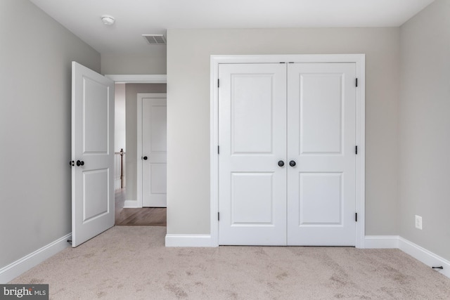 unfurnished bedroom with light carpet and a closet