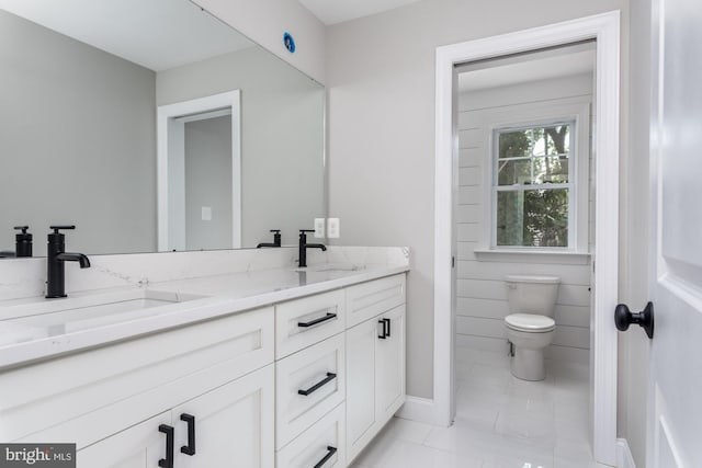 bathroom with toilet, vanity, and tile patterned floors