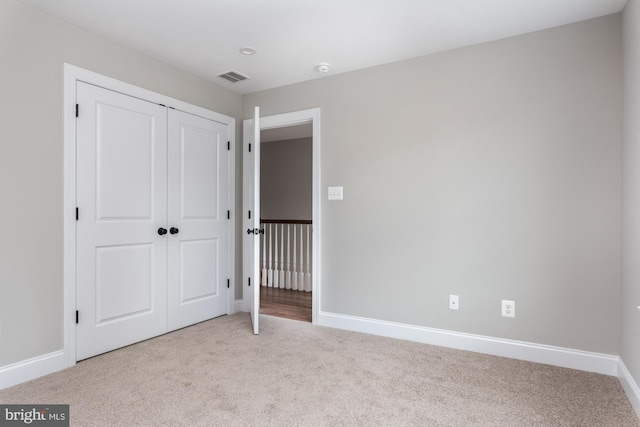 unfurnished bedroom with light carpet and a closet