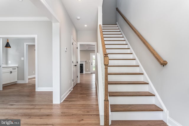 stairway with hardwood / wood-style floors and crown molding