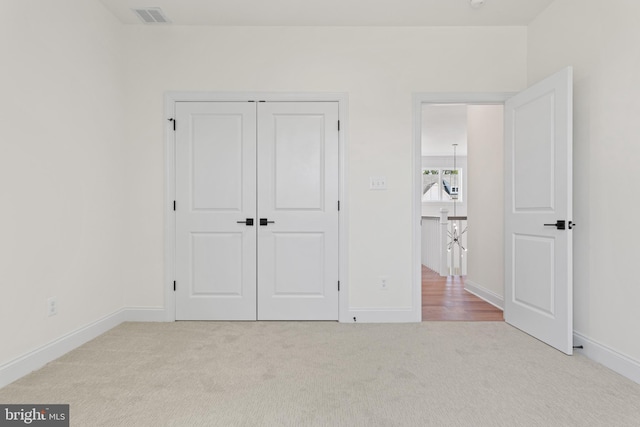 unfurnished bedroom with light colored carpet and a closet