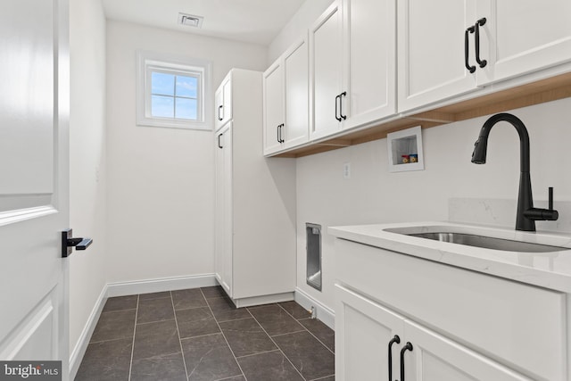 washroom featuring hookup for a washing machine, sink, dark tile patterned floors, and cabinets