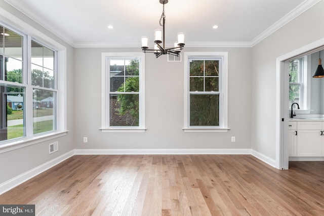 unfurnished dining area featuring a wealth of natural light, light hardwood / wood-style floors, and an inviting chandelier