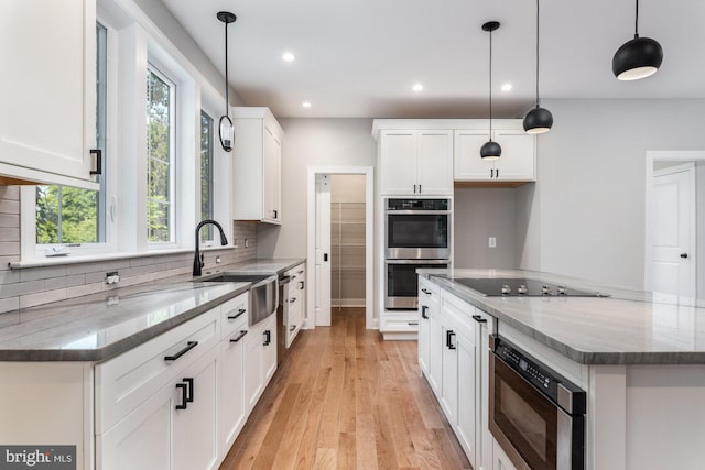 kitchen featuring light stone countertops, white cabinetry, hanging light fixtures, and black appliances