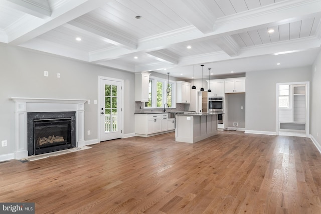 kitchen featuring white cabinets, light hardwood / wood-style flooring, a kitchen island, and pendant lighting