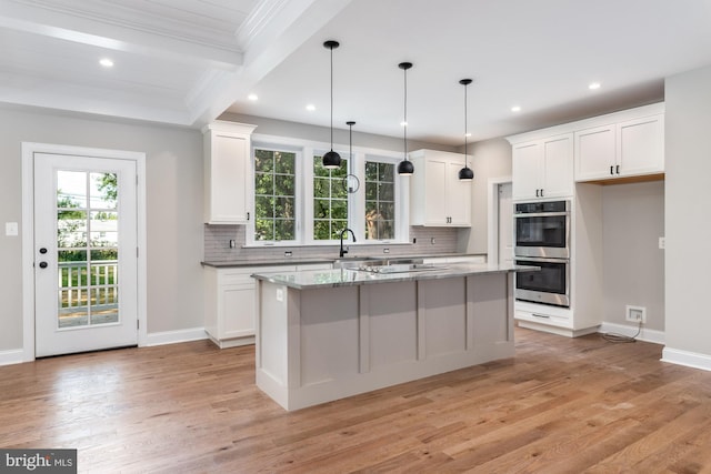 kitchen featuring light hardwood / wood-style floors, a center island, light stone counters, and white cabinetry