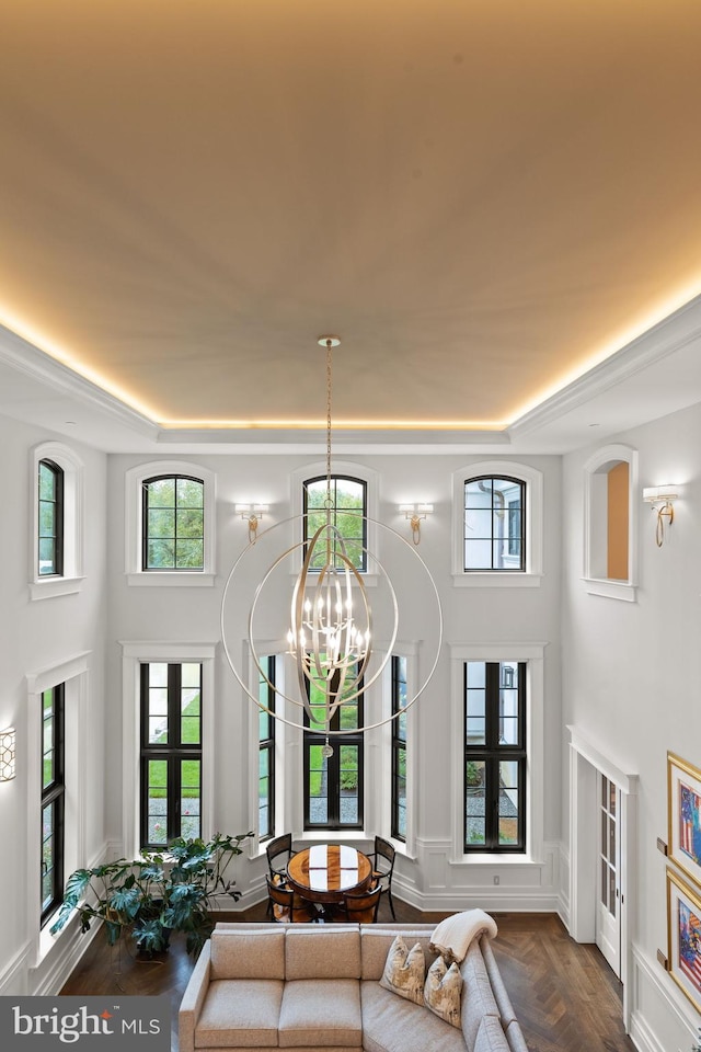 living room with a tray ceiling, french doors, parquet floors, and an inviting chandelier