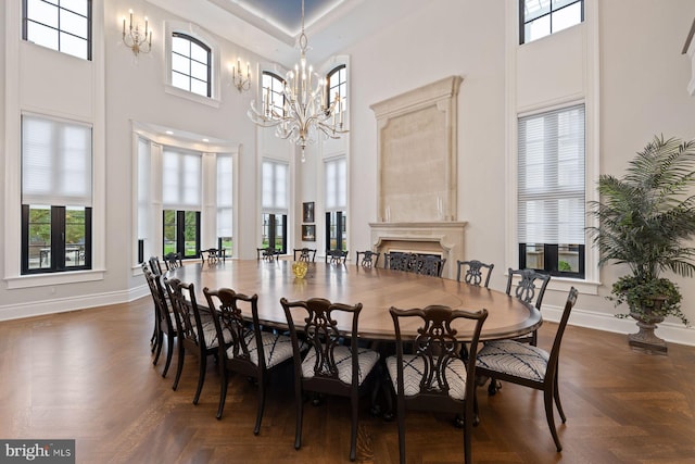 dining space with dark parquet flooring, a wealth of natural light, a high ceiling, and a notable chandelier