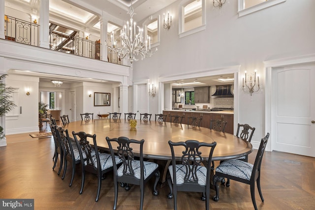 dining area featuring a towering ceiling, a chandelier, and parquet flooring