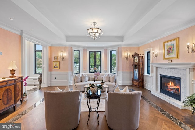 living room with a fireplace, french doors, a raised ceiling, and ornamental molding