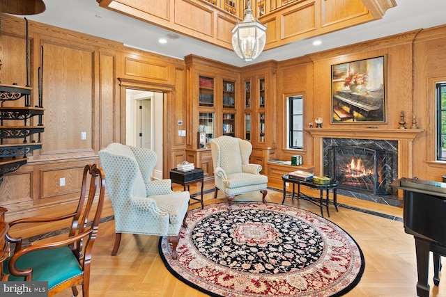 sitting room featuring a premium fireplace, light parquet floors, and wood walls