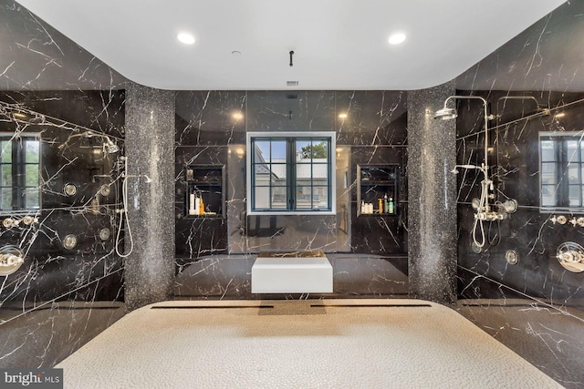 bathroom with a tile shower, plenty of natural light, and tile walls