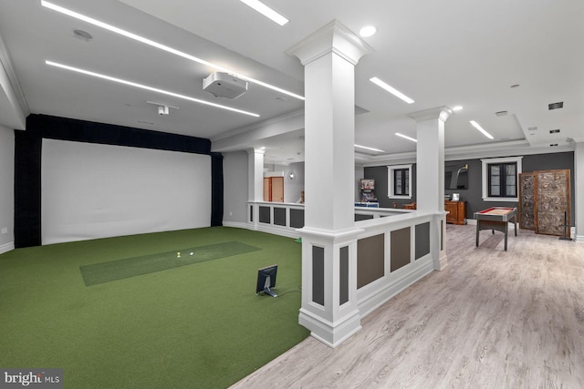 game room with decorative columns, light hardwood / wood-style flooring, golf simulator, and ornamental molding