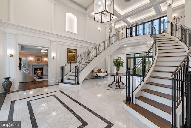 entryway featuring a towering ceiling, crown molding, a wealth of natural light, and coffered ceiling