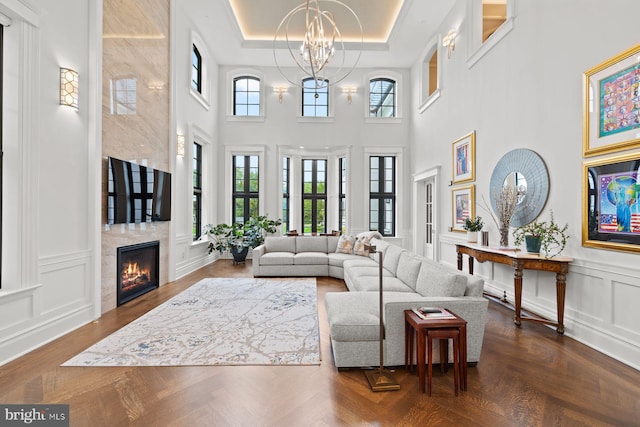 living room with a raised ceiling, dark parquet flooring, a towering ceiling, and a notable chandelier