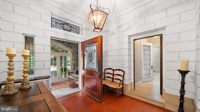 foyer featuring french doors, dark wood-type flooring, ornamental molding, and a chandelier