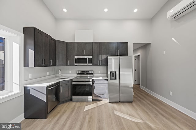 kitchen featuring a wall unit AC, light hardwood / wood-style floors, stainless steel appliances, and sink