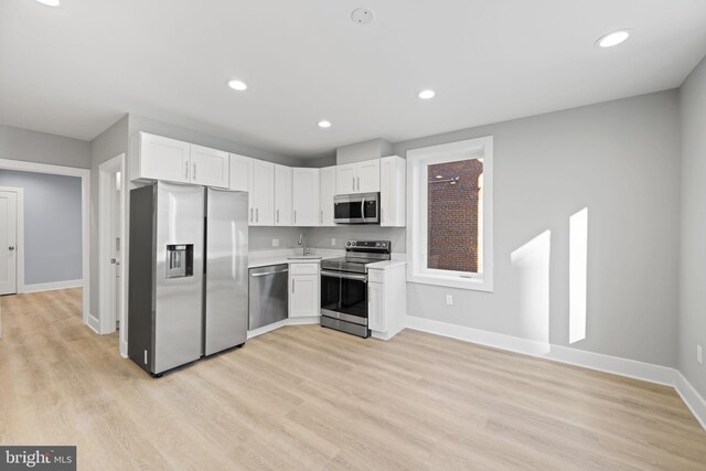 kitchen with white cabinets, sink, stainless steel appliances, and light hardwood / wood-style floors