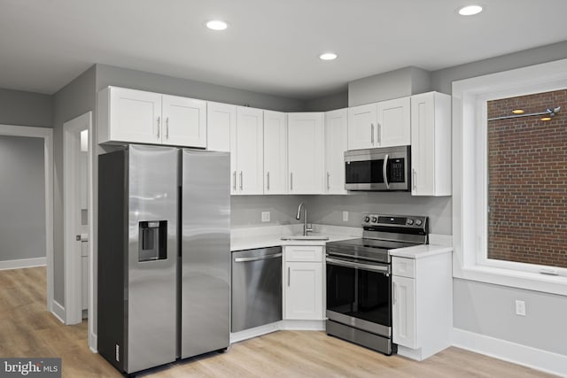 kitchen with light hardwood / wood-style floors, appliances with stainless steel finishes, white cabinetry, and sink