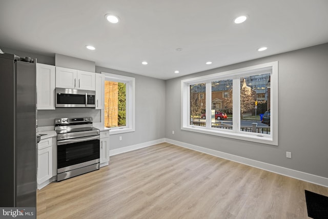 kitchen featuring appliances with stainless steel finishes, white cabinetry, and light wood-type flooring