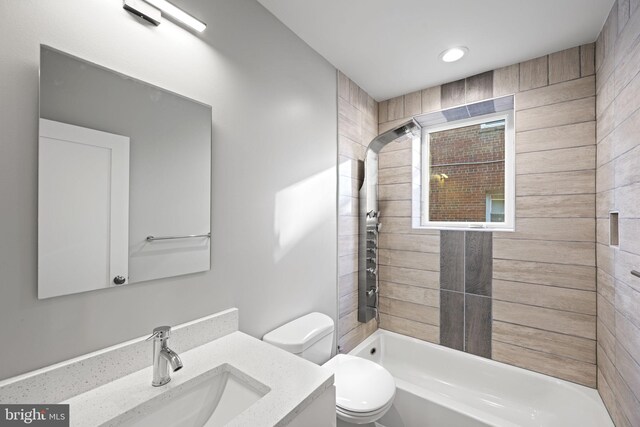 full bathroom featuring vanity, tiled shower / bath combo, and toilet