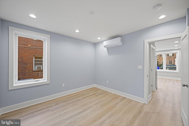 unfurnished room featuring a wall unit AC and light hardwood / wood-style floors