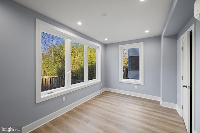 unfurnished bedroom featuring light hardwood / wood-style flooring and a wall mounted AC